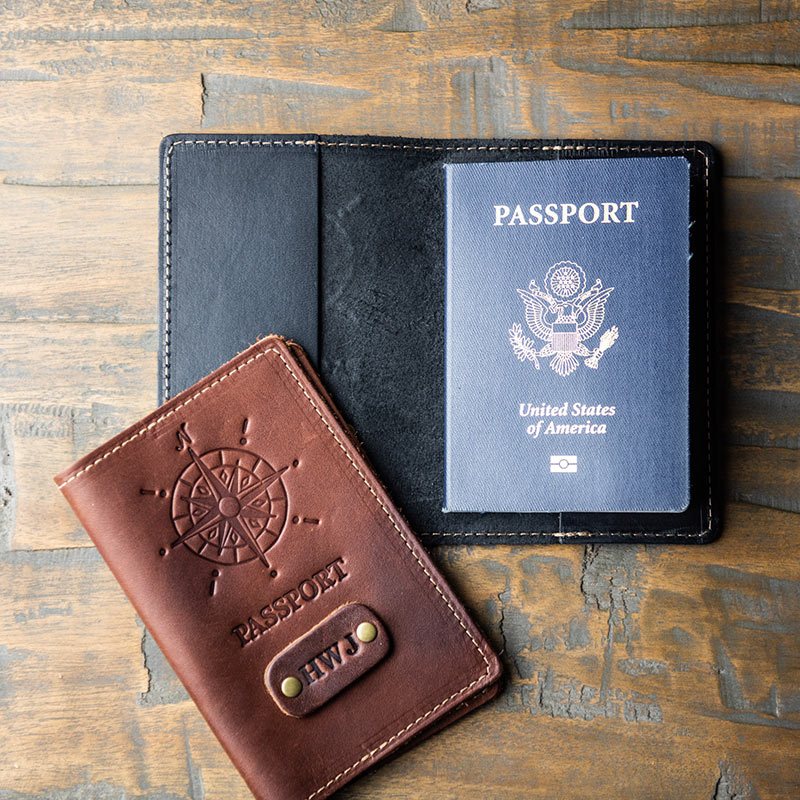 Outside of fine leather passport cover features a compass design and personalized initials; inside of passport cover features two pockets